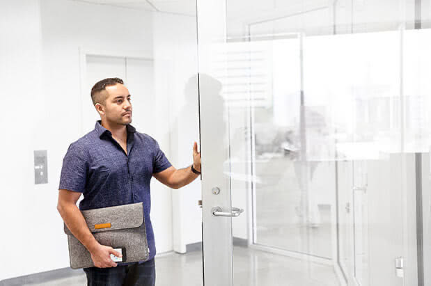 An employee holding a glass office door open