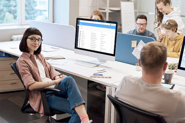 An office employee sitting in front of a computer screen showing the Klevio Dashboard