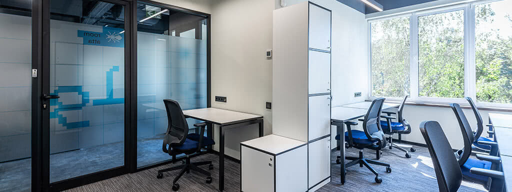 An office space with a door on the left and office desks on the right