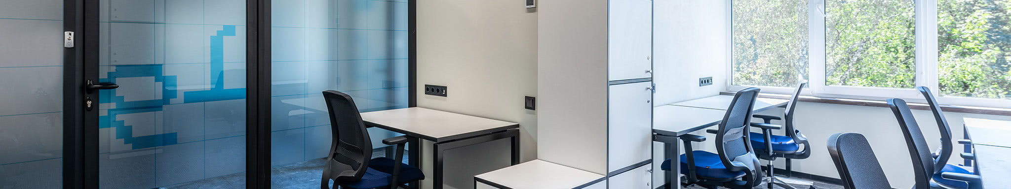 An office space with a door on the left and office desks on the right