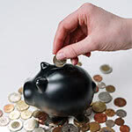 A hand putting coins into a piggy bank