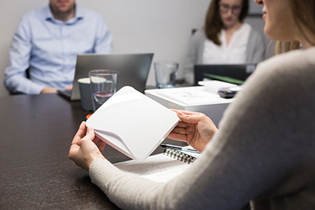 Woman holding a Klevio device at a board meeting