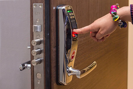 A person's hand interacting with a smart lock's door handle interface