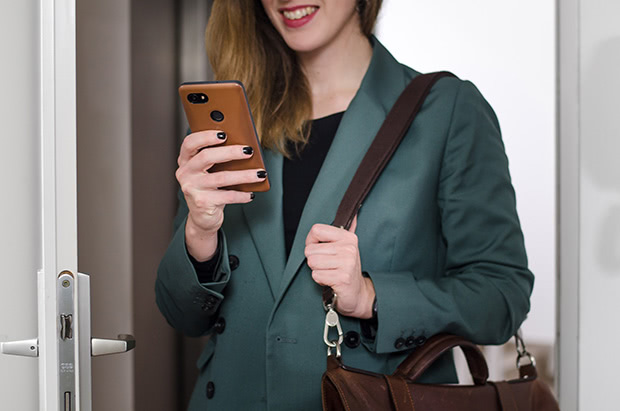 Smart lock user using a smartphone and entering through a door