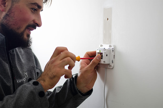 A professional installer mounting a Klevio device to a wall