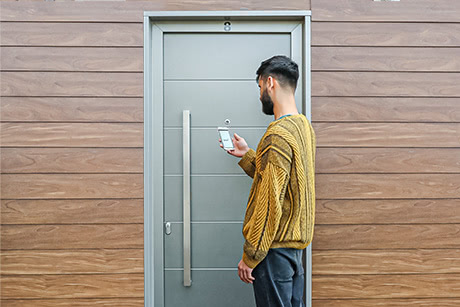 A uPVC door with a person in front of it, holding a smartphone with a Klevio smart lock app installed on it